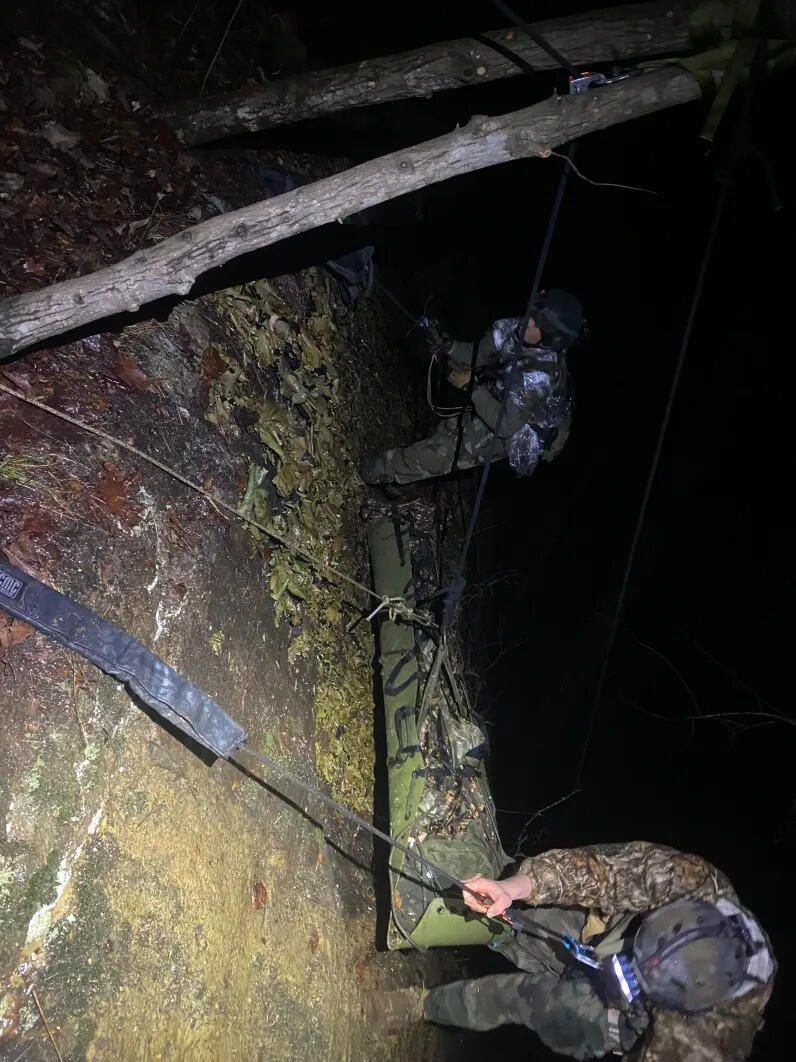Rescuers working a rock wall on rope at night