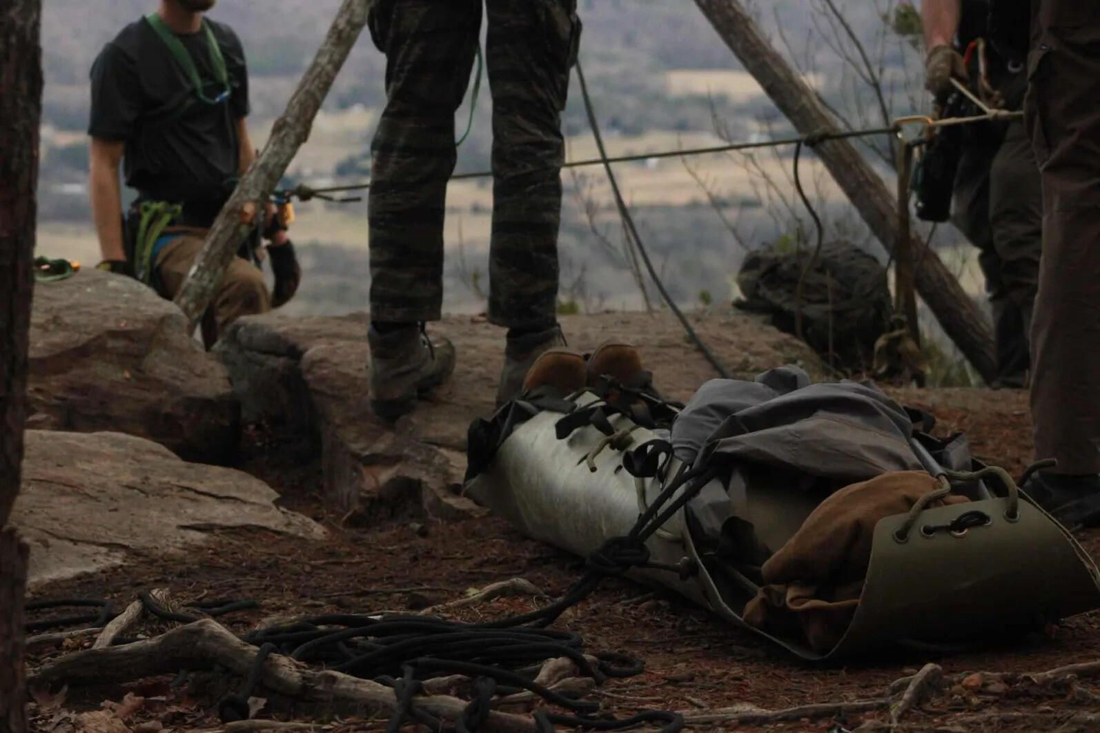 Packaging a casualty in a litter beside a tripod at a cliff overlook